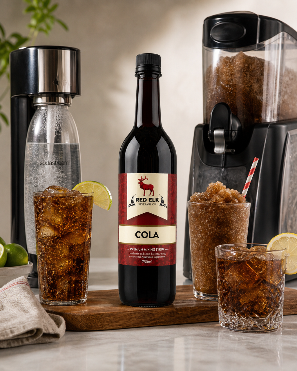 Red Elk Cola bottle with glasses of cola and a blender on a wooden board.