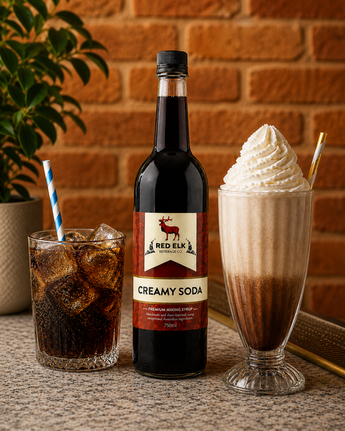 Bottle of Red Elk Creamy Soda syrup on bar with drink and milkshake