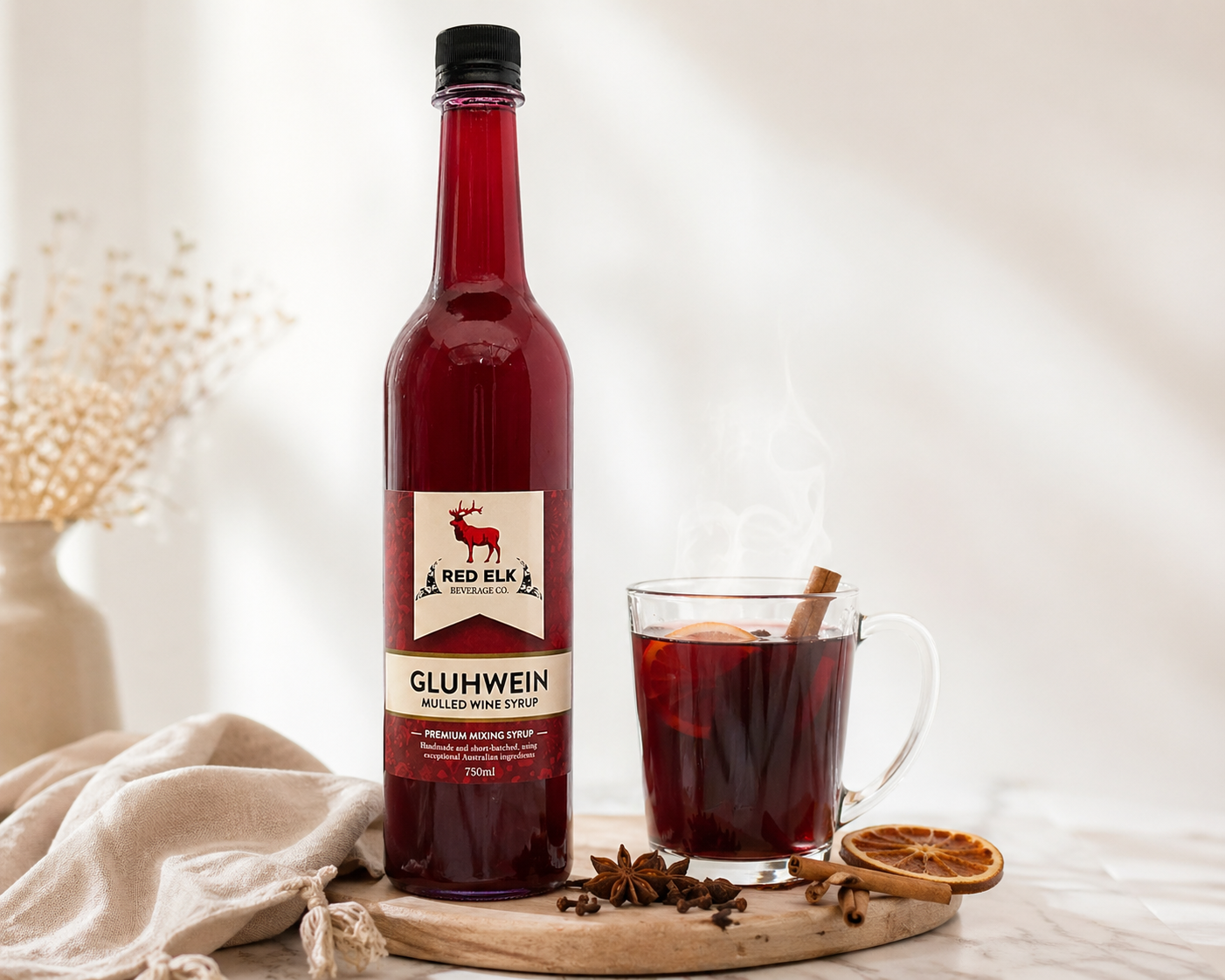 Bottle of Red Elk Gluhwein with a glass of mulled wine on a wooden board.