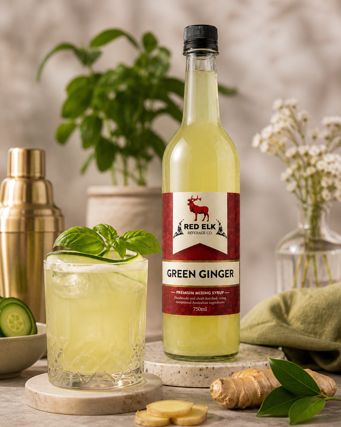 Bottle of Red Elk Green Ginger syrup with a cocktail and ingredients on a wooden surface.