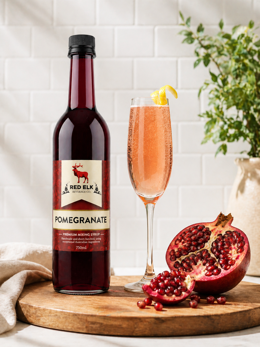 Bottle of Red Elk Pomegranate syrup with a champagne flute on a wooden board.