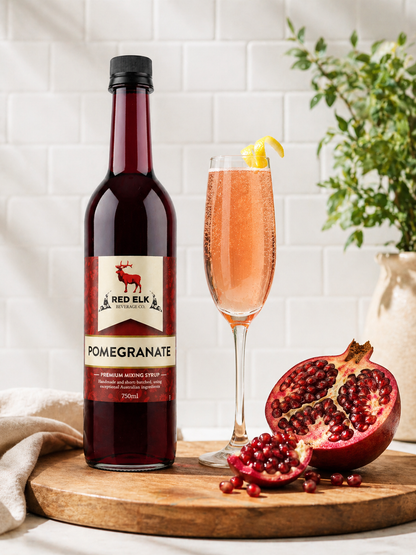 Bottle of Red Elk Pomegranate syrup with a champagne flute on a wooden board.