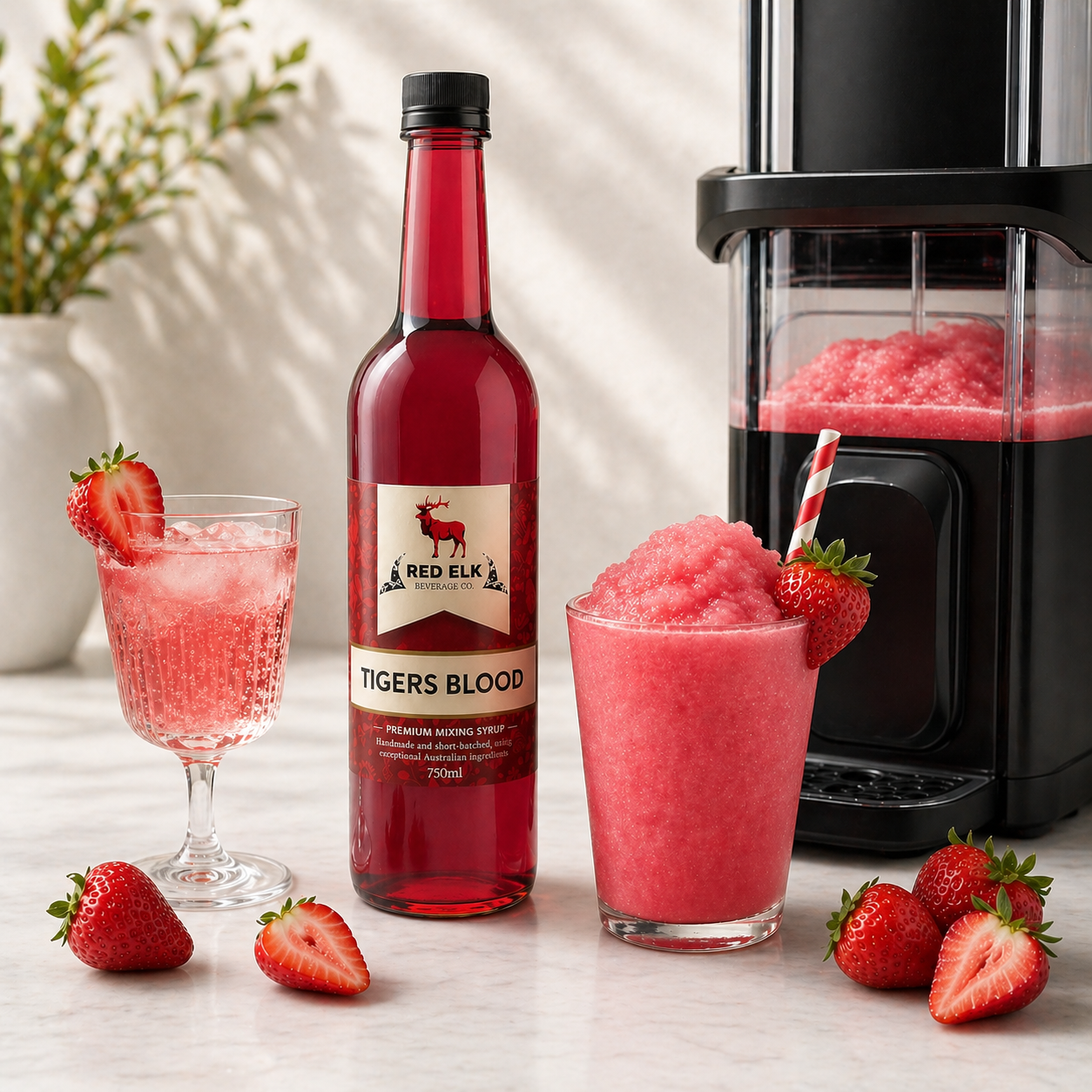 Red Elk Tigers Blood mixer bottle with a slushie and glass of pink drink on a table.